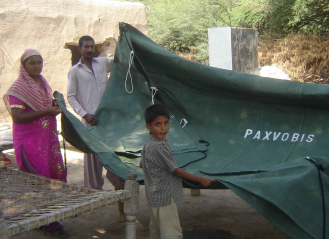 Pciture of a family with a tent donated by Paxvobis e. V. after the flood in 2010